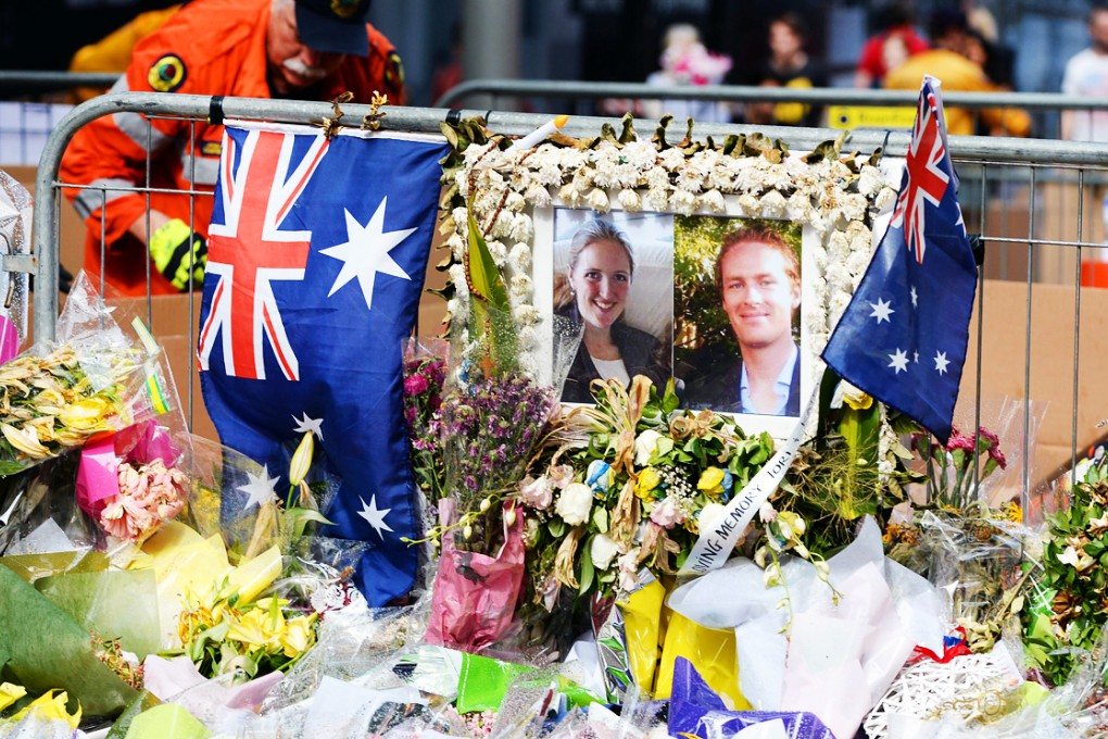 This file photo dated December 23, 2014, shows floral tributes and a photo of Katrina Dawson and Tori Johnson at a memorial site outside the Lindt cafe in Sydney, one week after the siege at the cafe in which the pair died. Photo: AFP
