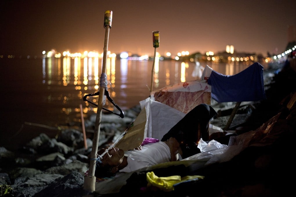 A homeless man beside Manila Bay. NGOs estimate 900,000 Filipino families sleep rough. Photo: AFP