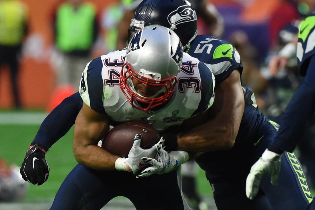 Shane Vereen (centre) of the New England Patriots is tackled by Bobby Wagner of the Seattle Seahawks during Super Bowl XLIX. The game is tied at half-time. Photo: AFP