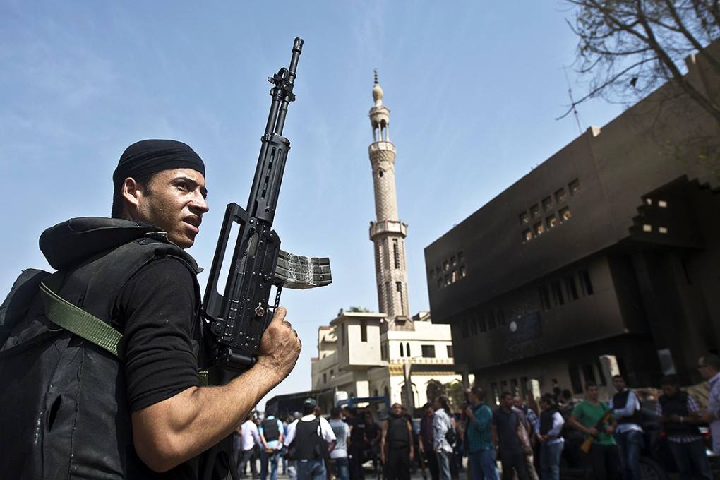 An Egyptian armed policeman holds a position in front of a burnt police station in the village of Kerdassah on the outskirts of Cairo in September 2013. Photo: AFP