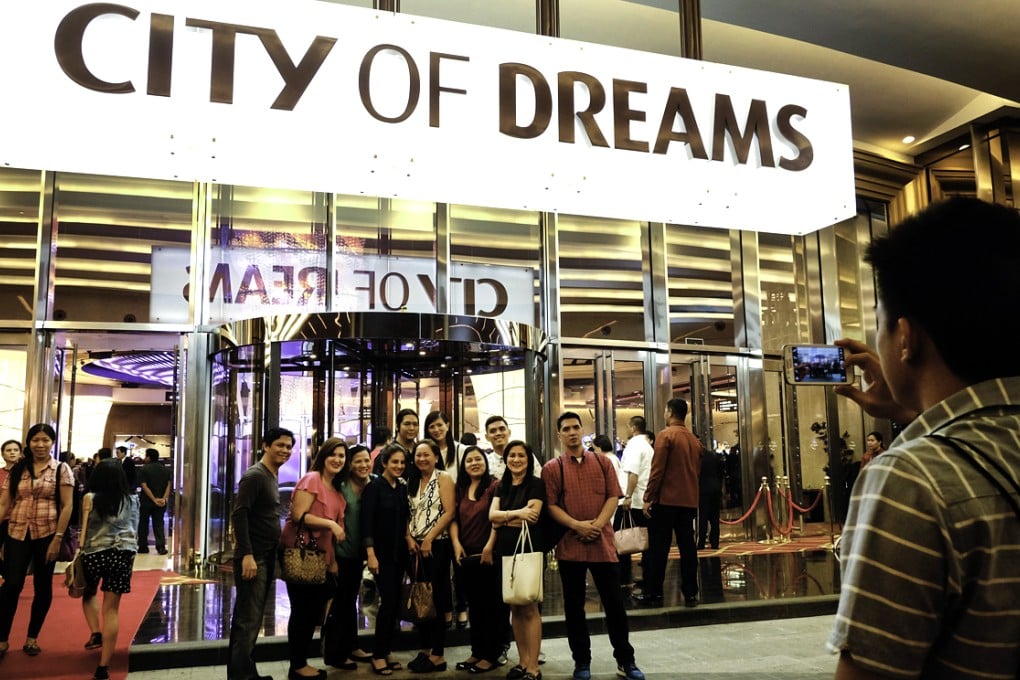 Visitors pose for a photograph below signage for the City of Dreams Manila casino resort in Manila, Philippines. Photo: Bloomberg