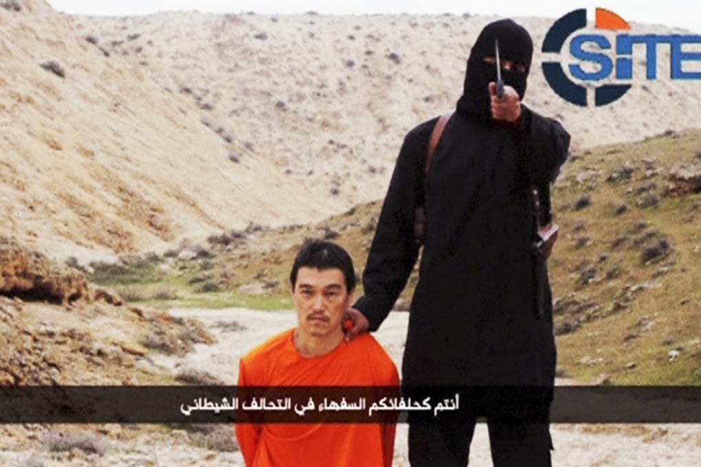 An Islamic State fighter stands next to Japanese journalist Kenji Goto kneeling on the ground. Photo: Reuters