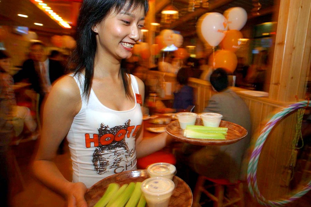 A Chinese waitress brings dishes around during the opening of Hooters in Shanghai. Photo: AP