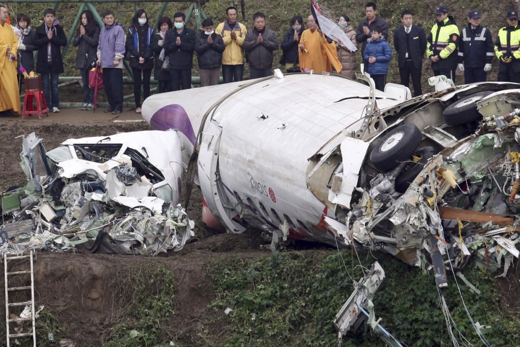 Relatives of victims of the TransAsia Airways crash pray on the banks of the Keelung River near the plane's wreckage yesterday. Photo: AP