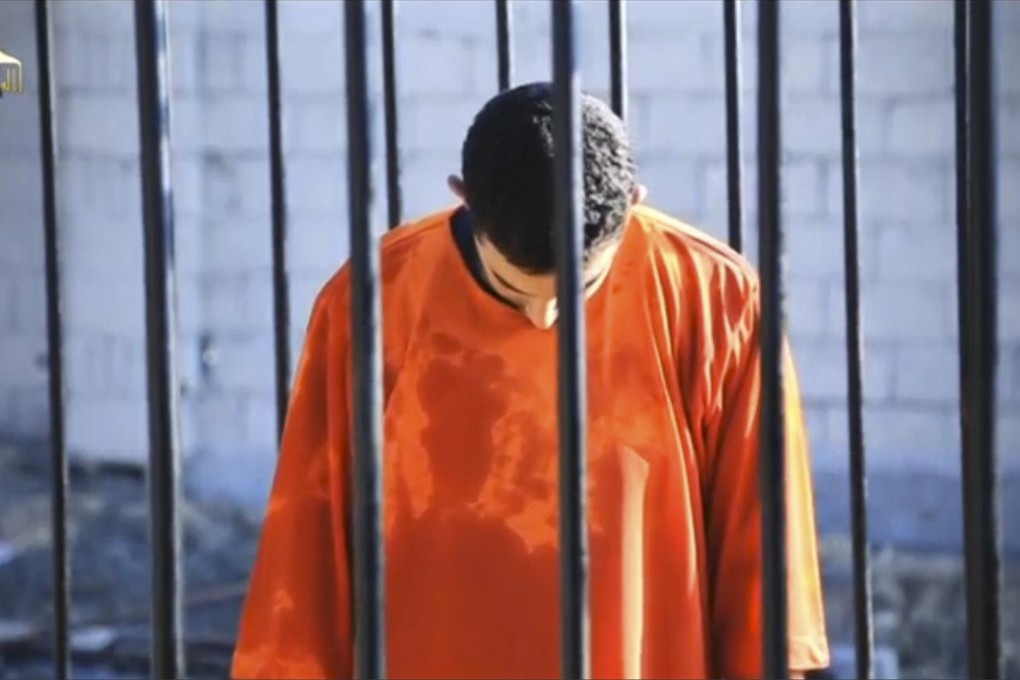 A caged Maaz al-Kassasbeh is seen with his head bowed shortly before being set on fire in a still from the horrific video. Photo: Reuters