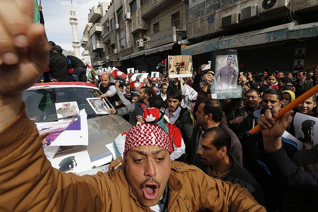 Jordanian protesters hold up pictures of Jordanian King Abdullah and Jordanian pilot Muath al-Kasaesbeh, as they chant slogans during a march after the Friday prayers in downtown Amman. Photo: Reuters
