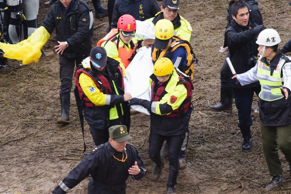 Workers carry a body away from the crash site. Photo: AFP