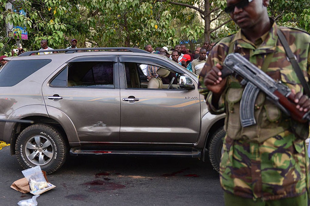 A police officer stands near the blood-stained vehicle of prominent government MP George Muchai after he was shot dead by gunmen in Nairobi. Photo: AFP