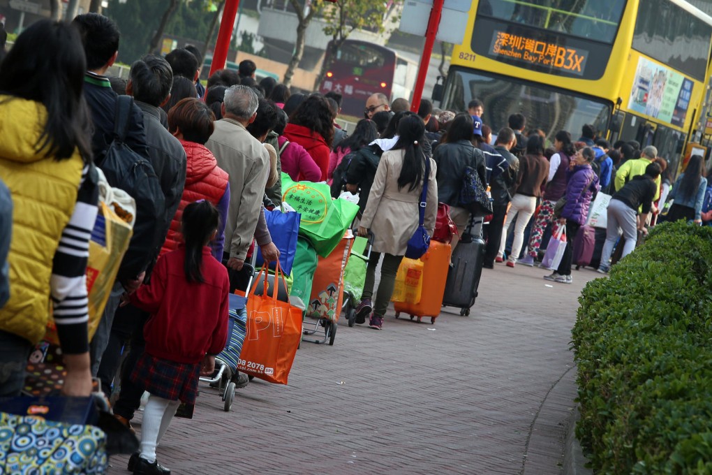 A long line of travellers waits with their purchases for a bus to the Shenzhen Bay border crossing. Hongkongers take different takes on the phenomenon. Photo: K. Y. Cheng
