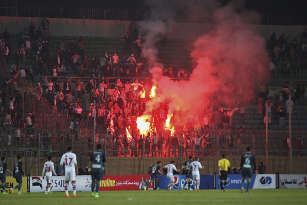 Soccer fans hold lit flares at the stand as they watch a match between Egyptian Premier League clubs Zamalek and ENPPI. A riot broke out outside the stadium reportedly over limited entry. Photo: AP