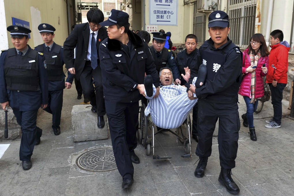 Police officers carry a man out of a Beijing hospital where he has been staying for more than three years. The man claimed doctors had injured his left leg during an operation in 2011 and refused to leave. Photo: Reuters