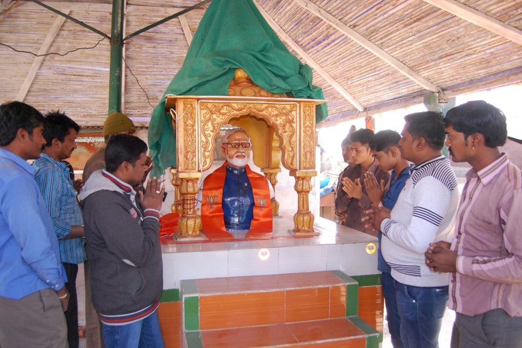 Villagers pray beside the Modi statue at the temple. Photo: AFP