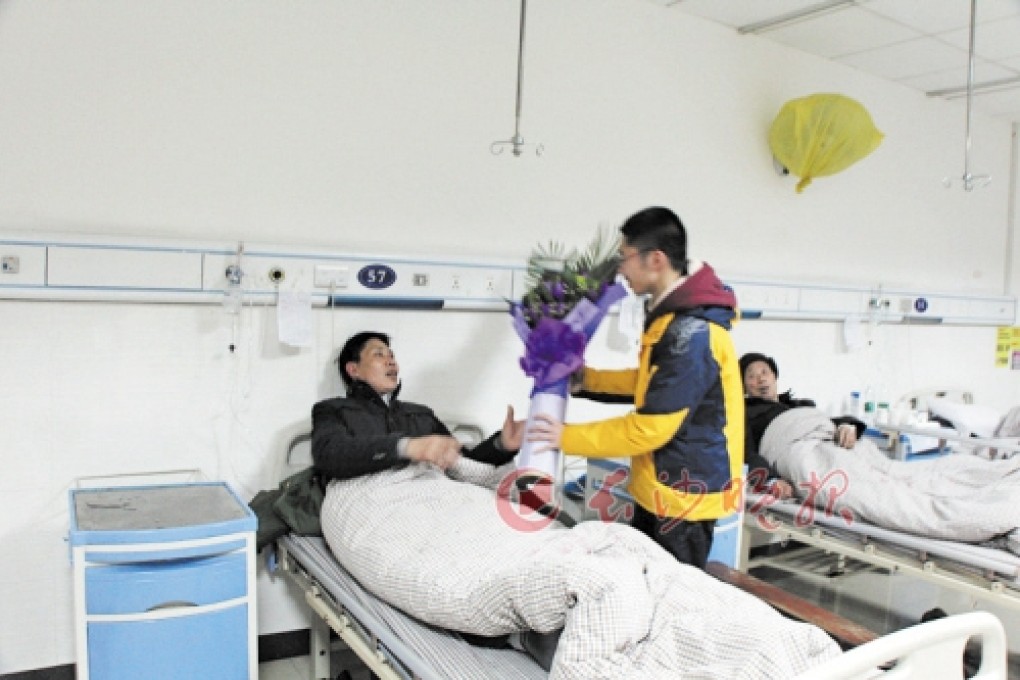 The 18-year-old college student visits the two sanitary workers whose lives he saved by pulling them out of a sewer and giving them CPR. Photo: Rednet.cn