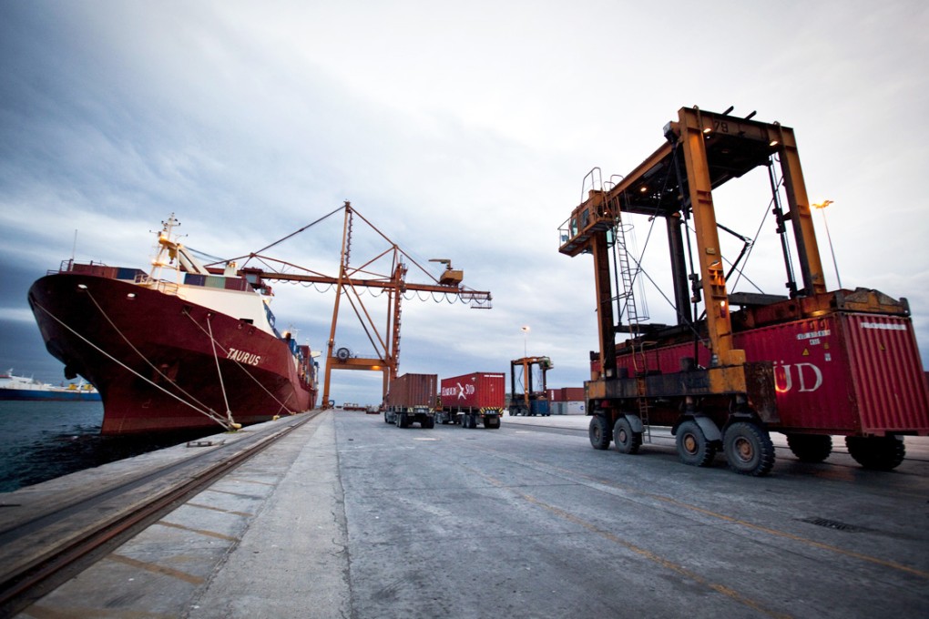 A transporter vehicle moves a shipping container from its transport ship to a storage location at the China Ocean Shipping Group Co. (COSCO) dock in Piraeus port, Athens, Greece. Photo: Bloomberg