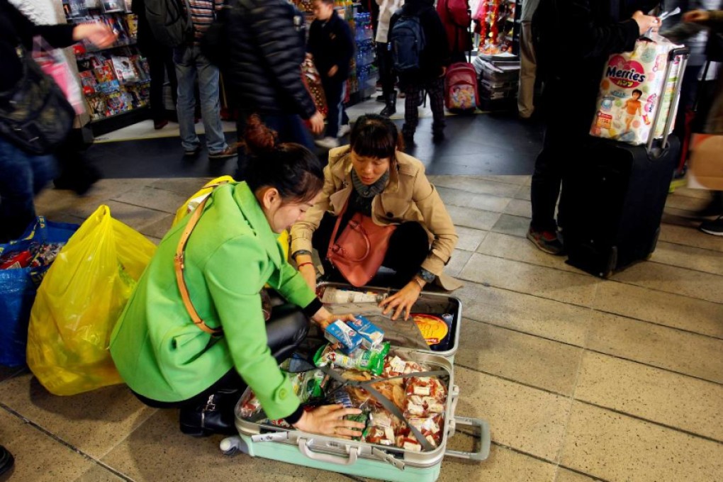 Mainland visitors pack their suitcase on the floor after shopping in Hong Kong. Photo: Reuters