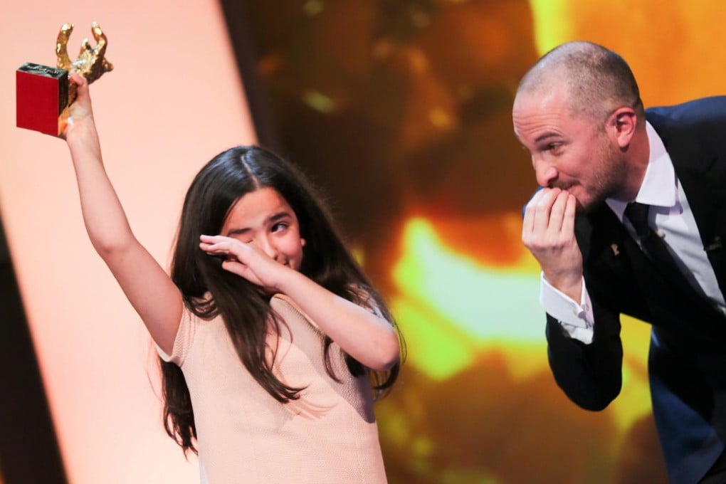 A tearful Hana Saeidi, the director's niece and a member of the film's cast, holds up the award at the ceremony in Berlin. Photo: EPA