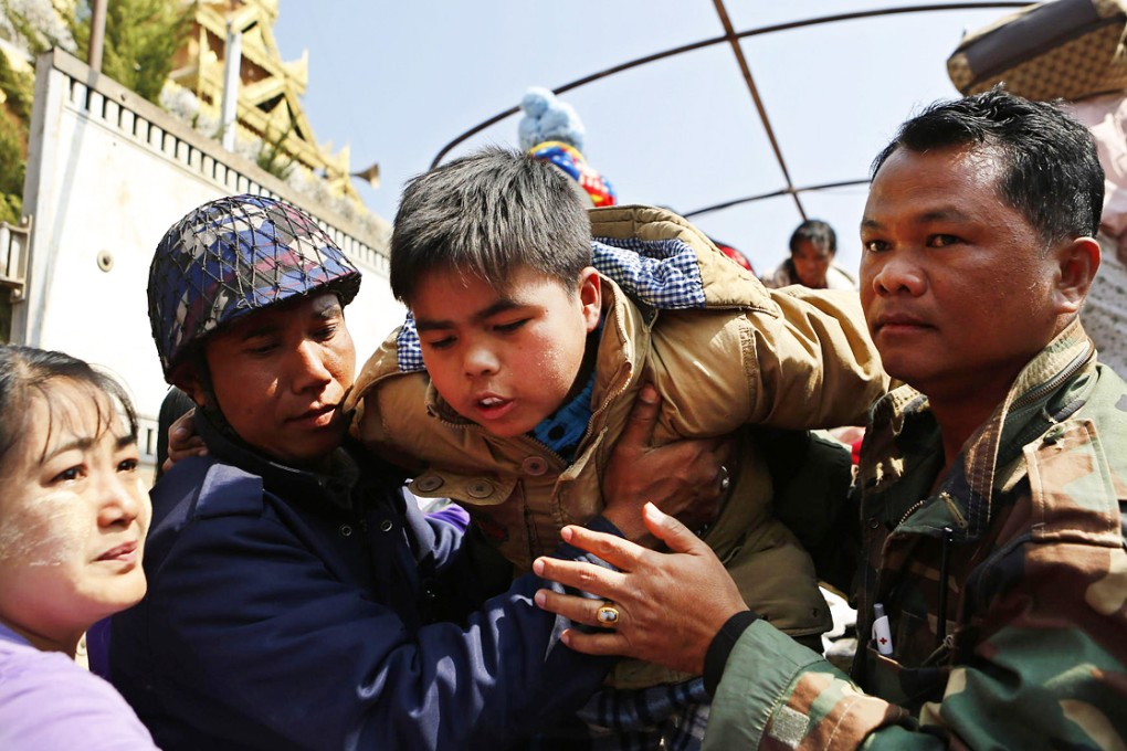 Military personnel help a child arriving in Lashio, northern Shan State, following fighting between troops and rebels. Thousands of people have fled the conflict zone. Photo: EPA