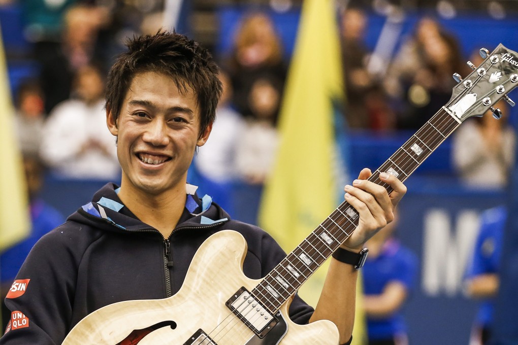 Kei Nishikori shows off the Gibson guitar he won. Photo: EPA