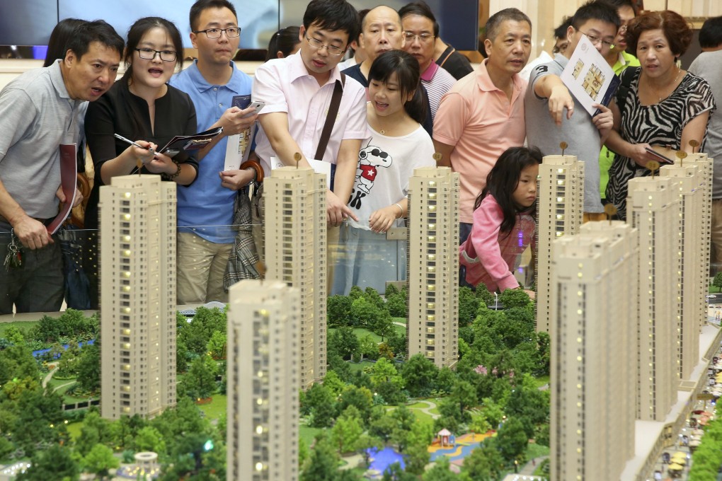 Homebuyers looking at a model of a new housing estate in Hangzhou in eastern Zhejiang province. Certificates for the new national property registration system will be introduced in March. Photo: Reuters