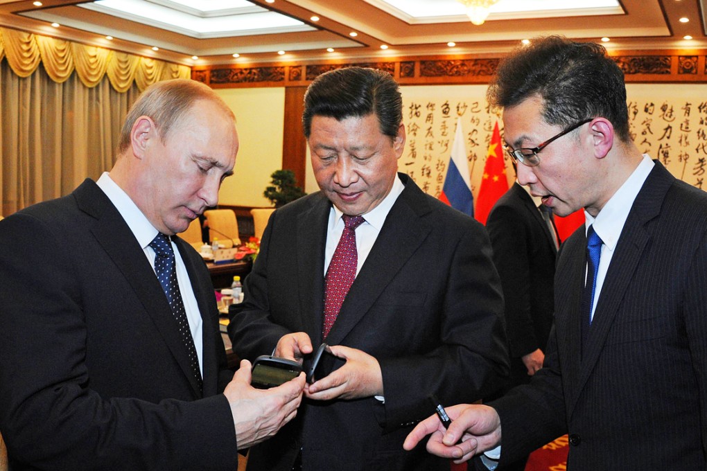 Chinese President Xi Jinping (centre) and Russian President Vladimir Putin (left) compare their mobile devices during their meeting at the APEC summit in Beijing late last year. Photo: AFP