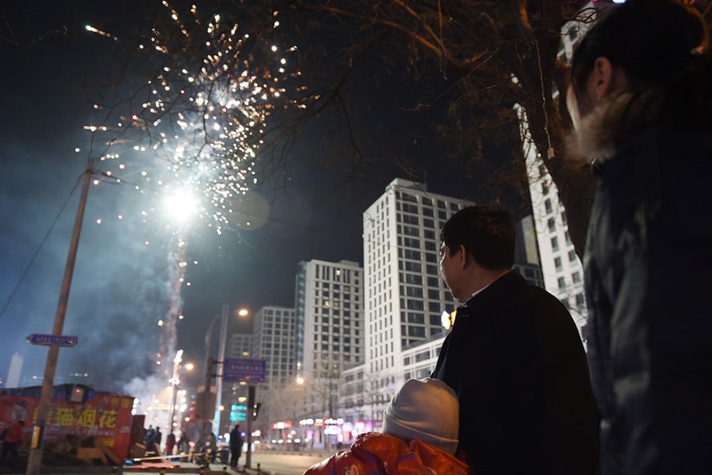 A family watches as people set off fireworks on the eve of the Lunar New Year in Beijing. Photo: AFP