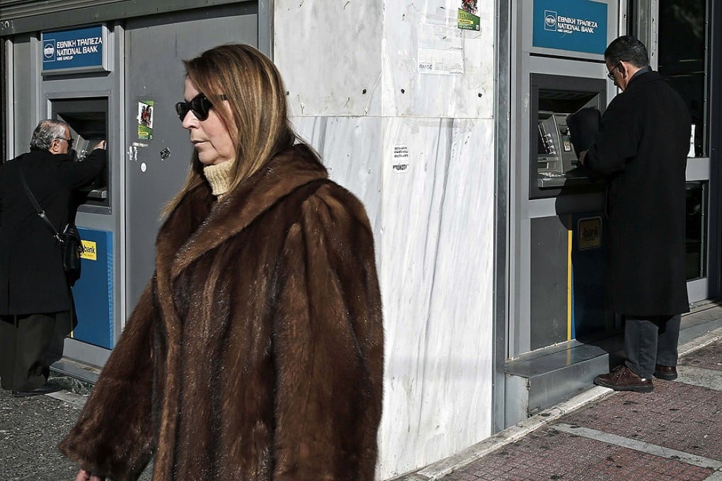 People make transactions at ATMs outside a National Bank of Greece branch in Athens. Photo: Reuters