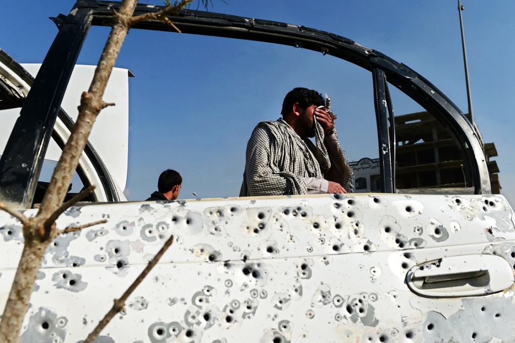A pedestrian walks past a shrapnel-riddled car door following an explosion from a magnetic bomb attached to a civilian car in Kabul. Photo: AFP