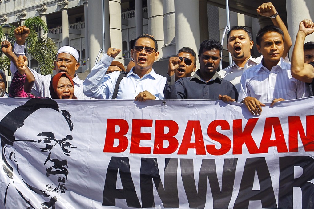 Supporters of Malaysian opposition leader Anwar Ibrahim hold a banner  reading 'Free Anwar' during a court case against Foreign Affairs Minister Anifah Aman in the Duta Court Complex, Kuala Lumpur on Febuary 17, 2015. Photo: EPA