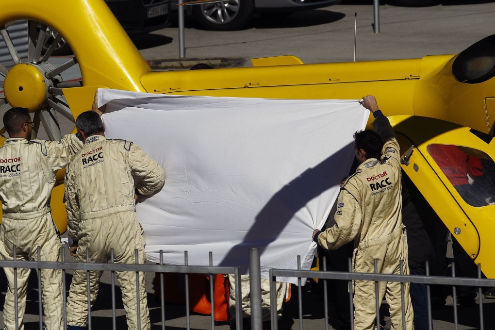 Fernando Alonso is shielded by teammates and medical staff as he is carried by stretcher to the evacuation helicopter. Photo: AFP