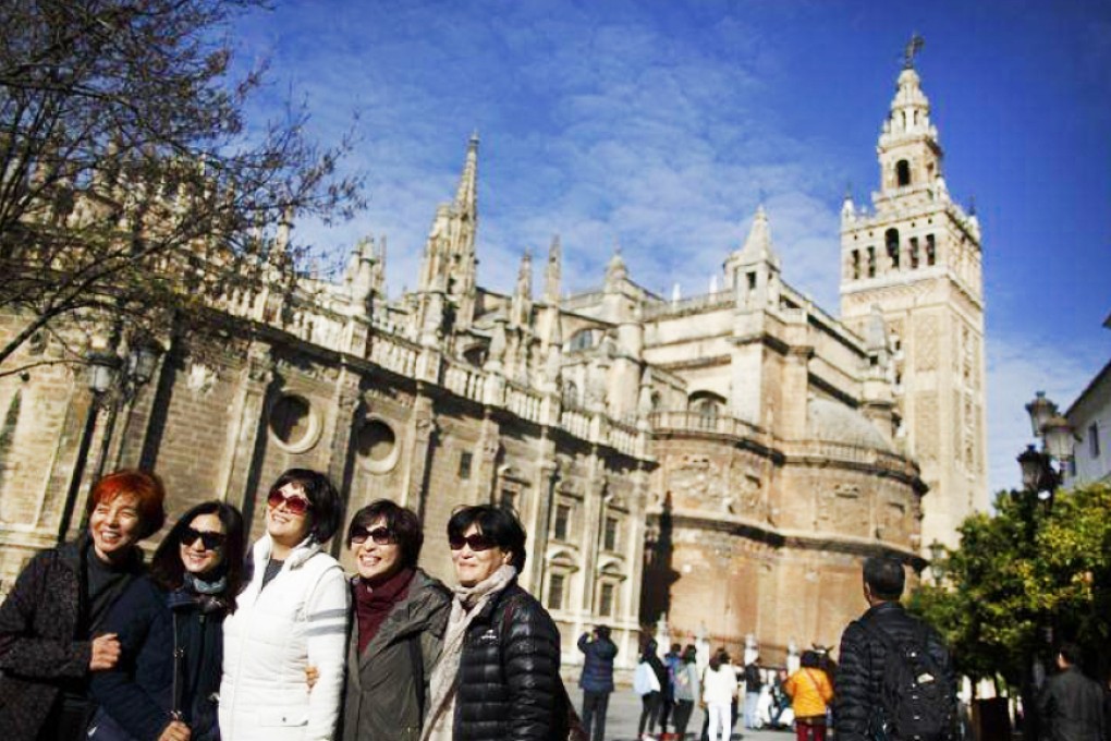 Tourists pose for photographs next to a cathedral in the Andalusian capital of Seville in southern Spain. Photo: Reuters