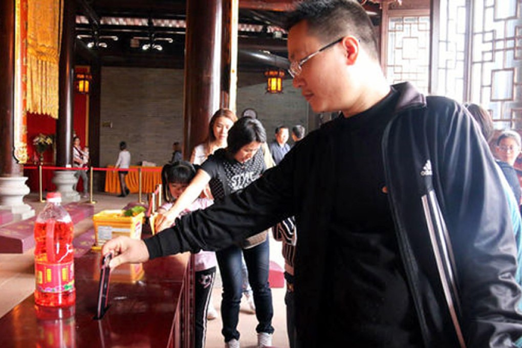 The man donates his phone at the temple. Photo: SCMP