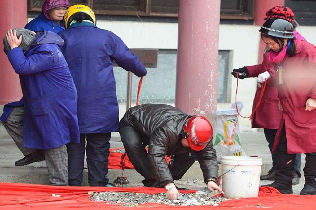 Workers at Wuhan's Guiyuan Temple in Wuhan don helmets as worshippers showered coins on the God of Wealth. Photo: SCMP Pictures