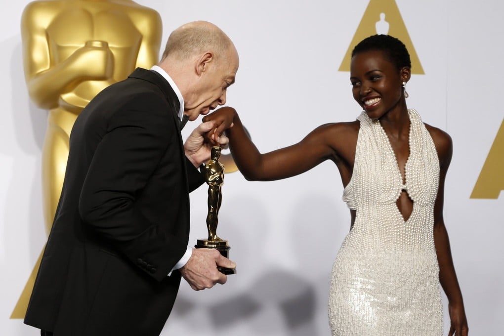 Academy Award winner JK Simmons kisses the hand of presenter Lupita Nyong'o backstage on Sunday night. Nyongo's dress, stolen from her hotel room on Wednesday, was covered in 6,000 pearls. Photo Reuters