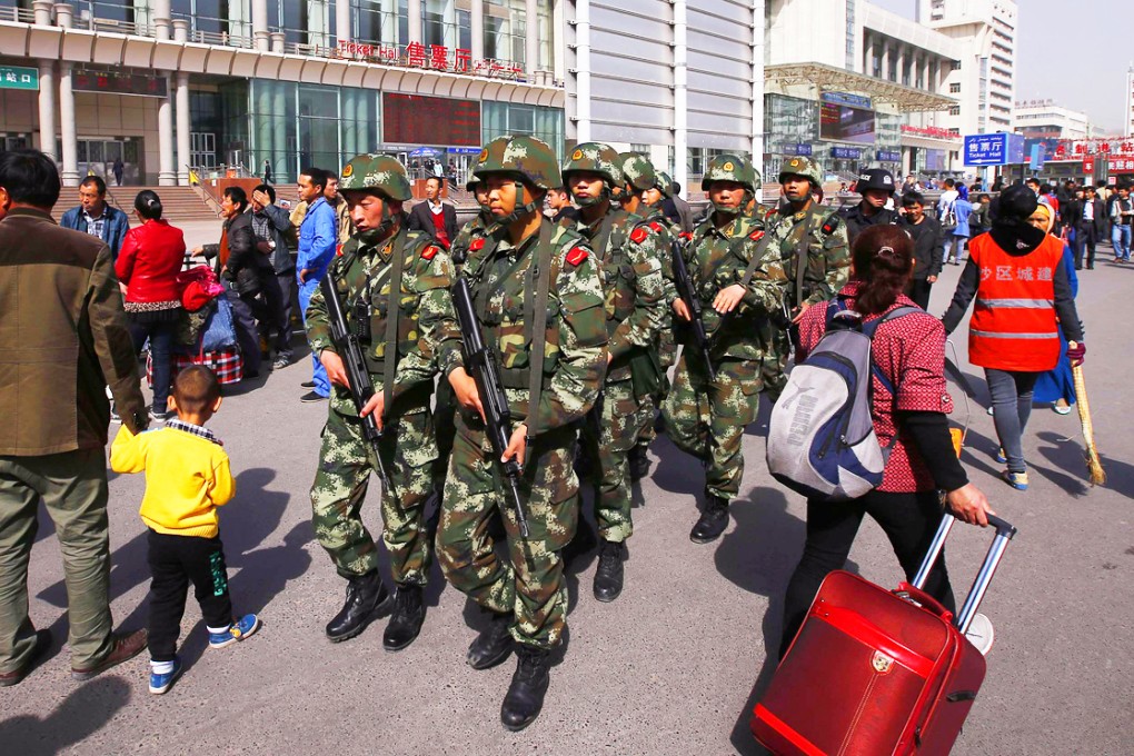 Armed Chinese police patrol near the exit of Urumqi's South Railway Station after last May's bomb and knife attack in Xinjiang, which left three people dead. Photo: Reuters