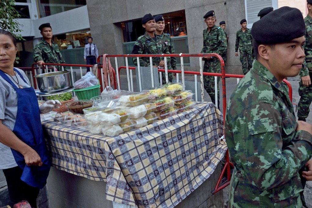 Soldiers walk past a vendor in Bangkok. Thousands of hawkers are set to be relocated. Photo: AFP