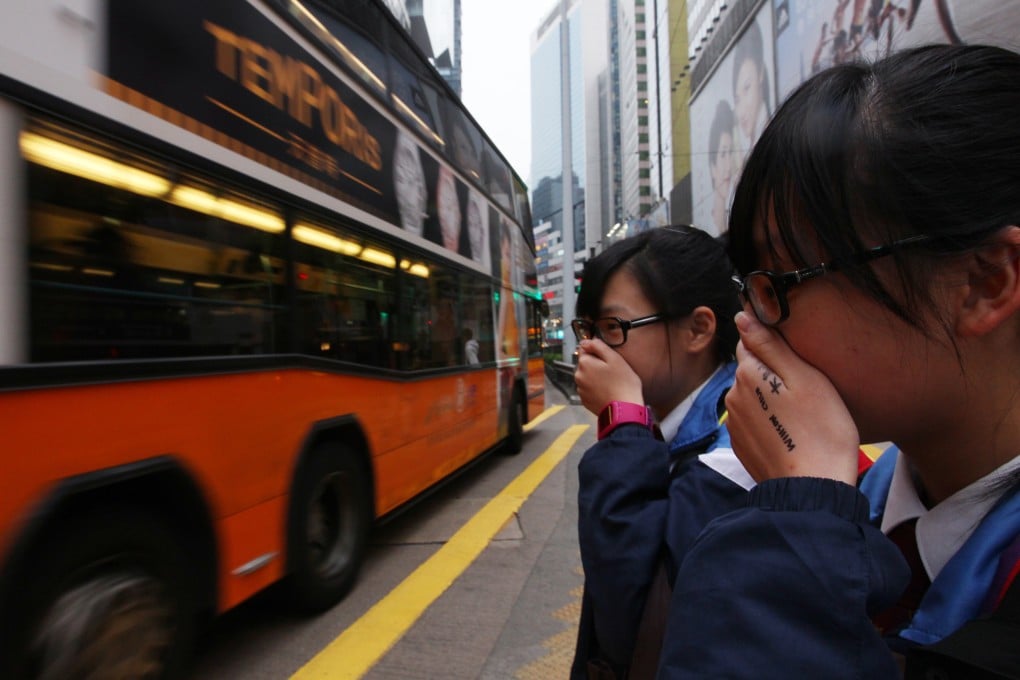 Students cover their faces to avoid breathing in fumes in Causeway Bay as the city struggles with its pollution problem. Photo: Nora Tam