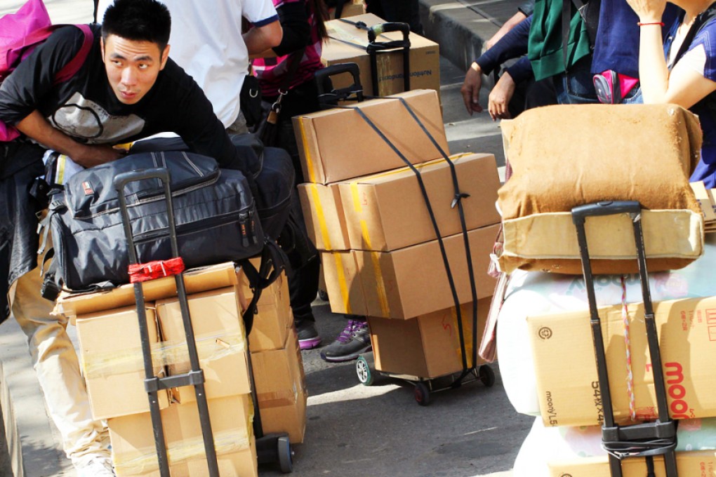 Parallel-traders who snap up items such as baby formula and diapers wait in line to carry their goods across the border at Sheung Shui railway station. Photo: Felix Wong