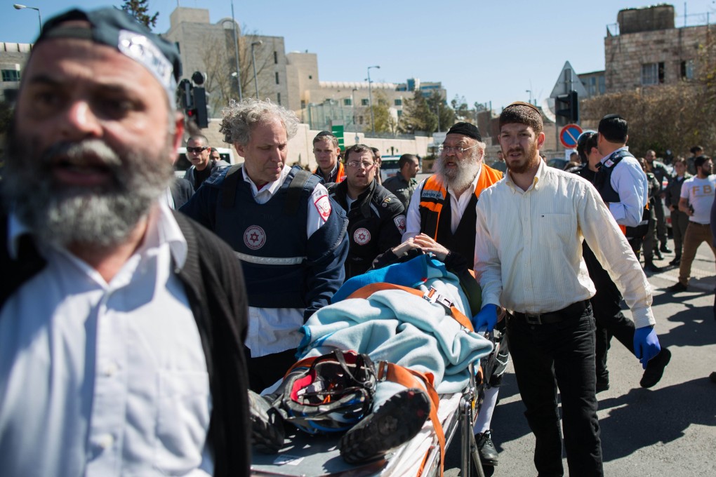 Israeli medics and police carry an injured man away after the latest ramming attack in Jerusalem. Photo: AFP
