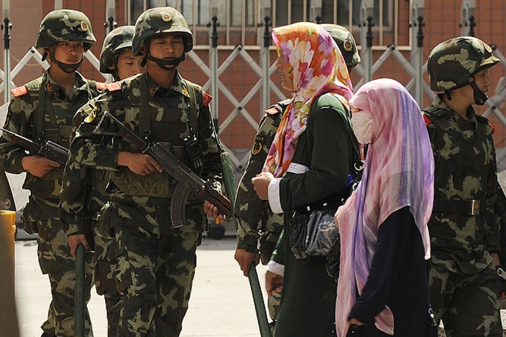 Uygur women pass a paramilitary police patrol on a street in Urumqi, the capital of Xinjiang. Photo: AFP