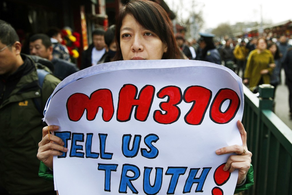 Catherine Gang, whose husband Li Zhi was onboard the missing Malaysia Airlines flight MH370, holds a banner in Beijing. Photo: Reuters