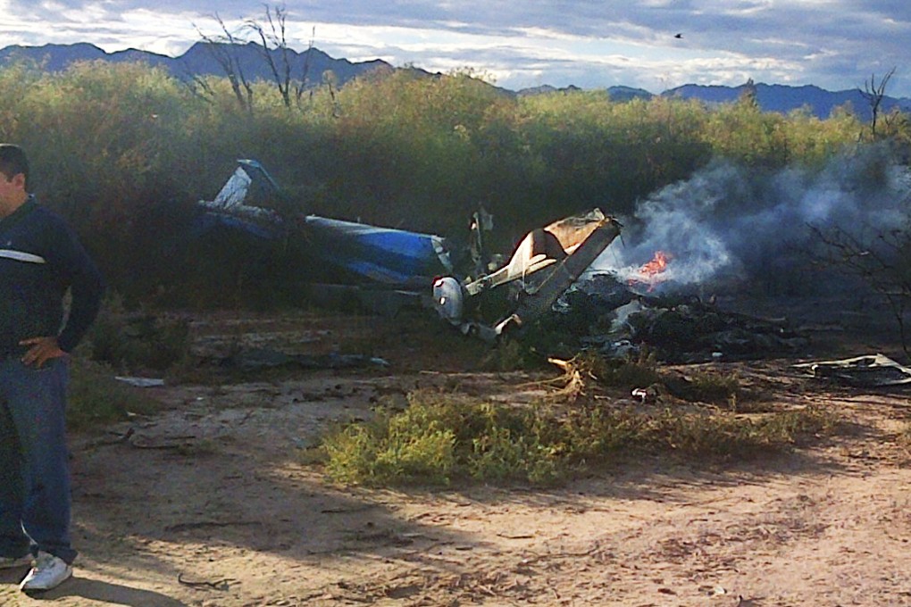 A man stands near the smoking remains of a helicopter that crashed with another near Villa Castelli in the La Rioja province of Argentina. Photo: AP