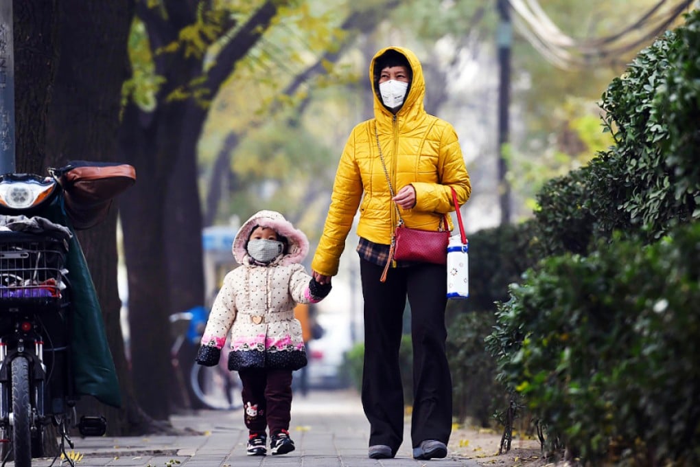 A woman and child wear masks as they walk on a polluted day in Beijing on November last year. Photo: AFP