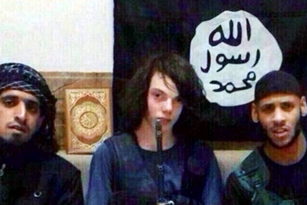 Jake Bilardi, flanked by two older Islamic State members, poses in front of the group's flag. Photo: SCMP Pictures