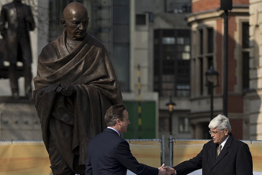 British PM David Cameron and Gandhi's grandson Gopalkrishna Gandhi (right) shake hands beneath the new statue of Mahatma Gandhi in Parliament Square, London on Saturday. Photo: AP