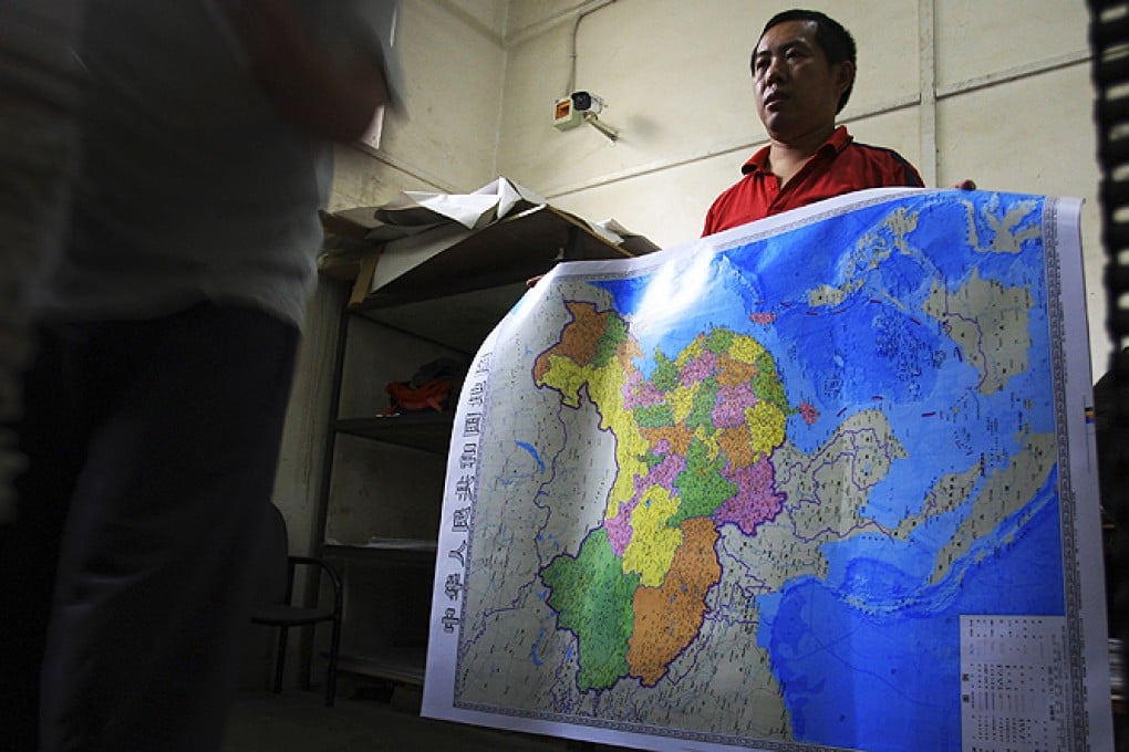 A print worker holds an officially-approved map of China that includes the areas Beijing claims in the South China Sea in this file picture from June 2014. Photo: AP