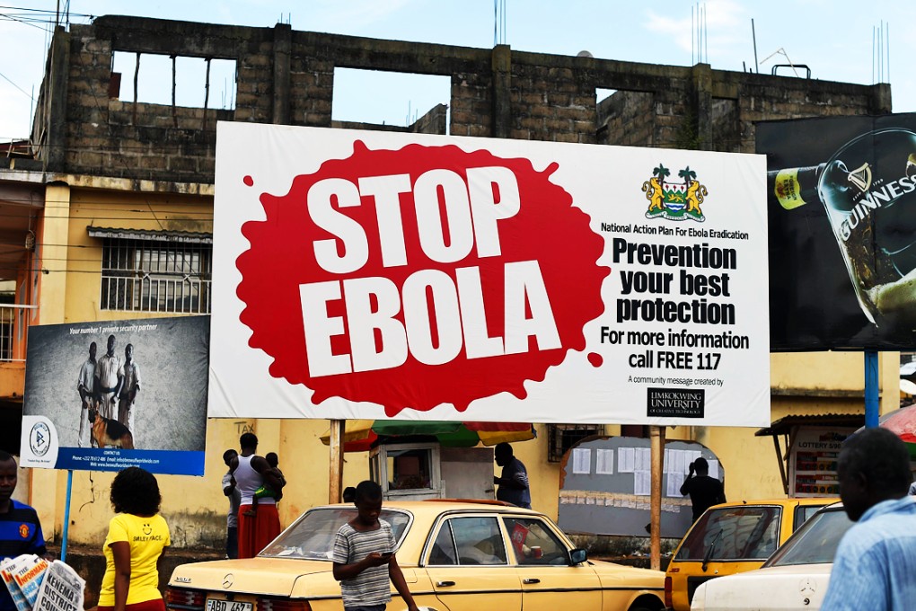 People walking past a billboard reading "Stop Ebola" in Freetown. Photo: AFP