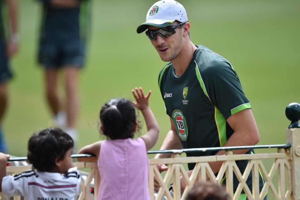 Australia bowler Pat Cummins interacts with a young fan during a training session. Photo: AFP