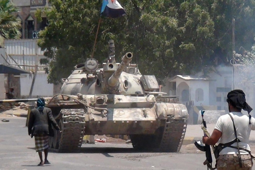 An armed man stands guard in front of a tank in Aden, Yemen. Air raids began in the country late last week. Photo: AFP