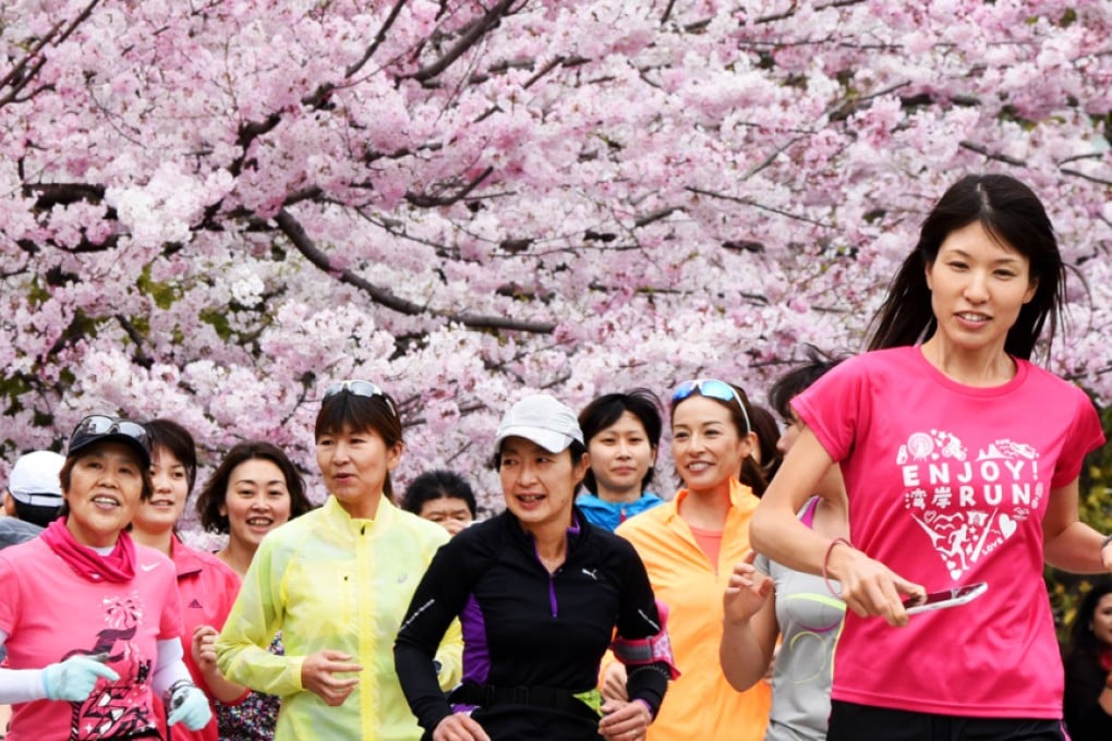 Joggers run past cherry blossom in Tokyo on Sunday. Photo: AFP