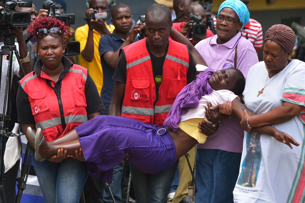 Members of the Red Cross carry a relative of one of the students massacred by Somalia's Shebab Islamists as families pour in to identify the bodies. Photo: AFP